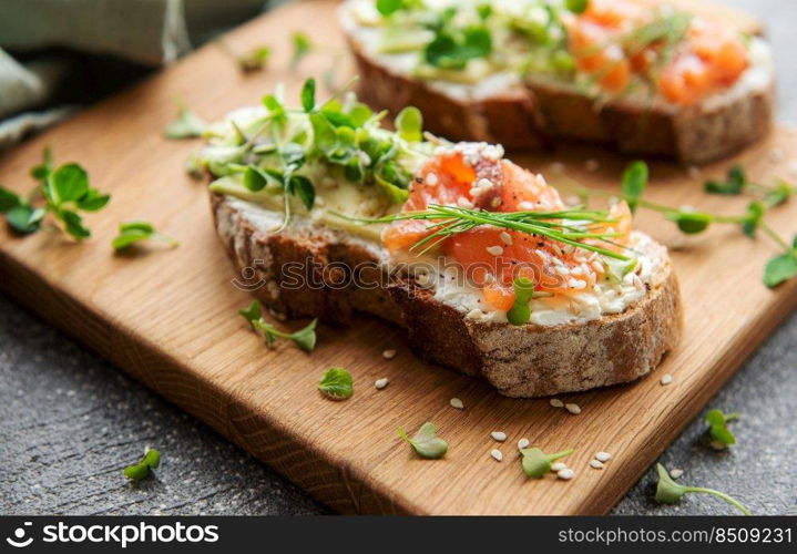 Sandwiches with salted salmon,  avocado and microgreens.  Healthy food.