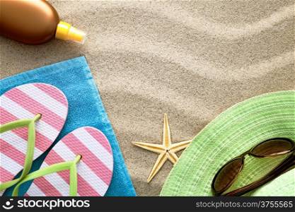 Sandy beach background with towel, flip flops, hat, sun glasses, suntan oil and starfish. Summer concept. Top view