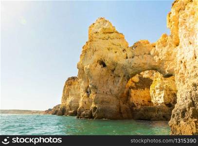 Sandy cliffs in the ocean in sunny hot day, Algarve, Portugal. Ocean with sandy cliffs