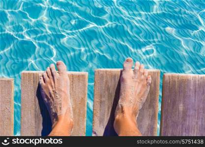 sandy feet on the pier under tropical turquoise water sea ocean