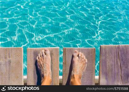 sandy feet on the pier under tropical turquoise water sea ocean
