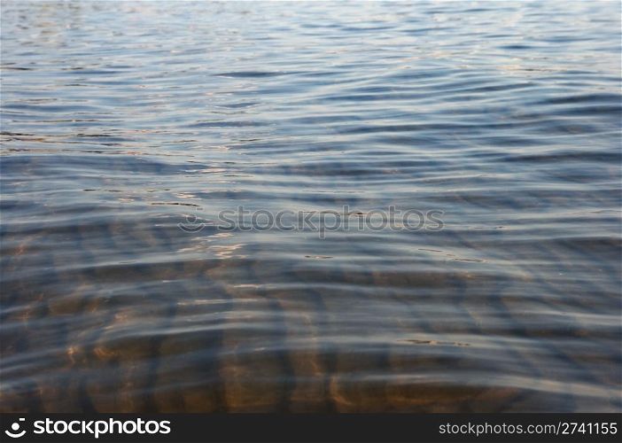 Sandy sea bottom in through water and waves on surface