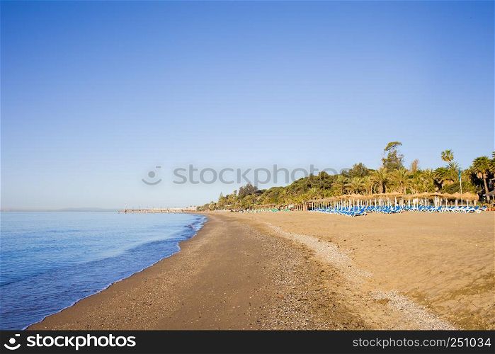 Sandy, wide, long, empty beach on Costa del Sol in Marbella holiday scenery in Spain, Malaga province.