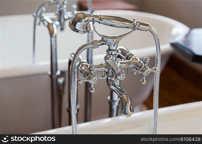 sanitary, plumbing and washing concept - close up of bath tap and shower at bathroom
