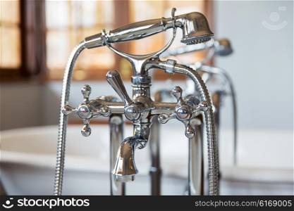 sanitary, plumbing and washing concept - close up of bath tap and shower at bathroom