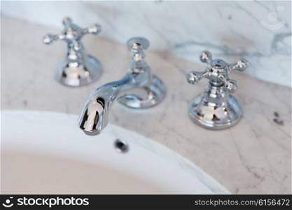 sanitary, plumbing and washing concept - close up of bath tap or faucet at bathroom