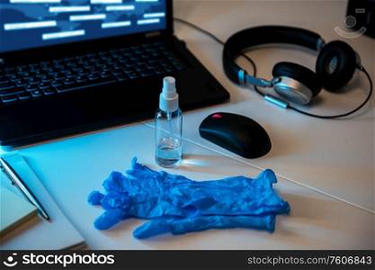 Sanitizer anti virus spray with protecive gloves on the working table with laptop, mouse, headphones. Personal hygiene concept. Concept of quarantine for coronavirus and working from home.. Sanitizer anti virus spray