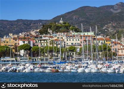 Sanremo, Italy ? November 14, 2017 - sunny day view from the sea with boats and yachts to the old town of Sanremo (La Pigna) and Madonna della Costa Church on the hilltop, Liguria, Italy