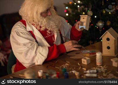 Santa Claus at Home making toys and painting