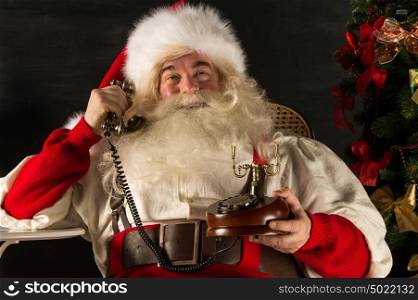 Santa Claus calling by vintage phone. Sitting near Christmas tree at home
