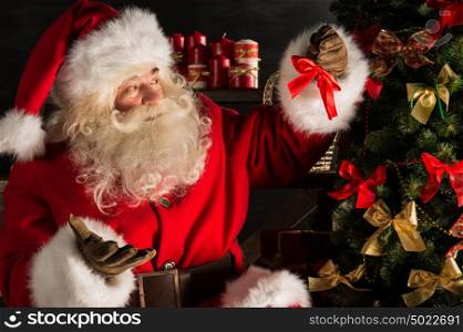 Santa Claus decorating Christmas tree in dark room