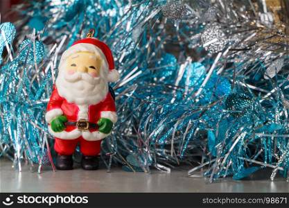 Santa Claus figurine and blue and silvery tinsel as decoration for Christmas