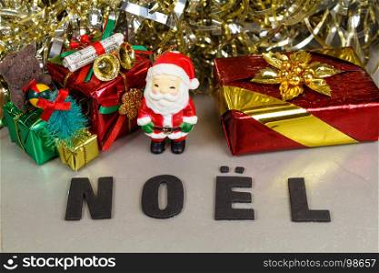 Santa Claus figurine with gift, golden tinsel and the word Christmas in French