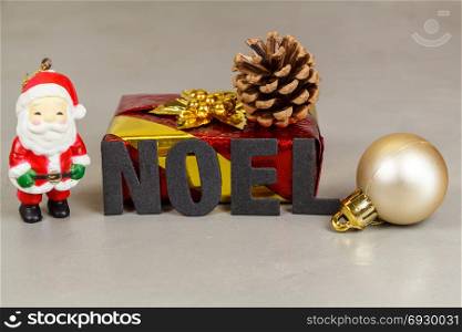 Santa Claus figurine with gift, pine cone, bauble and the word Christmas in french