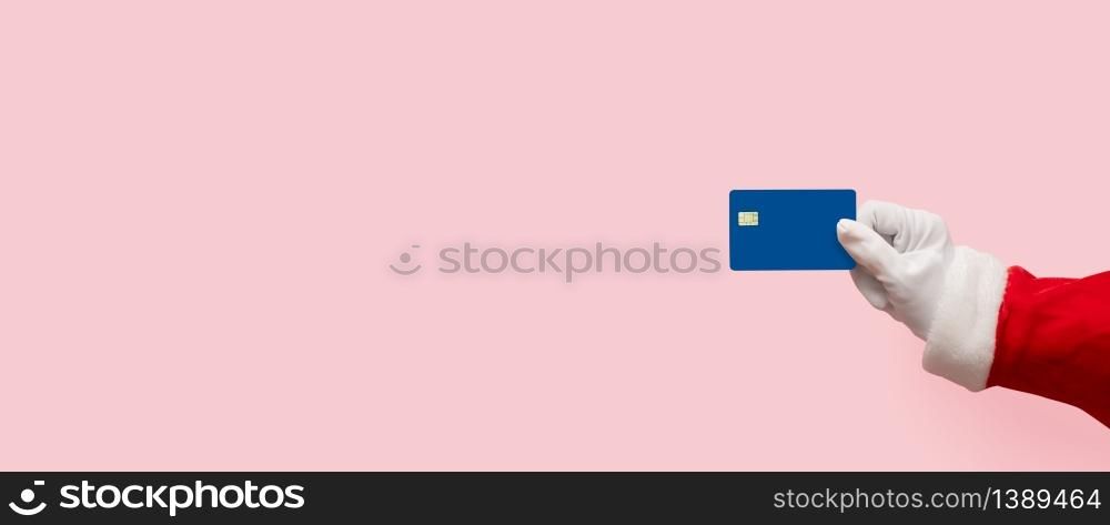 Santa Claus hand holding plastic credit card over pink isolated background. Shopping, Sales, Giving Gift for Black Friday, Christmas and New Year 2019 concepts.