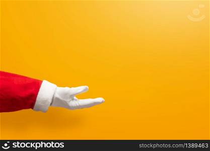 Santa Claus hand on yellow or orange isolated background with copy space. Christmas, Birthday and New year 2019, 2020 concepts.