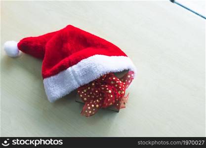 Santa Claus hat with Gift boxes placed on wooden table interior of room view through window with tree Background with Copy Space,Decoration During Christmas and New Year.
