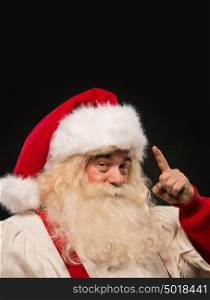 Santa Claus have an idea gesturing with finger against dark background. Lots of copyspace
