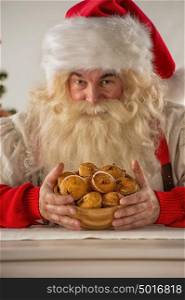 Santa Claus holding cookie or cupcake at home