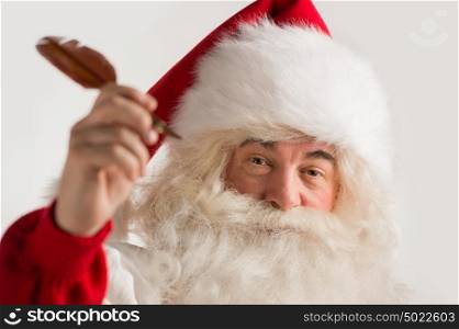 Santa Claus holding feather pen in his arm and writing