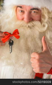 Santa Claus holding keys of new house or apartment and thumbs up, standing near Christmas tree. Good mortgage offer concept