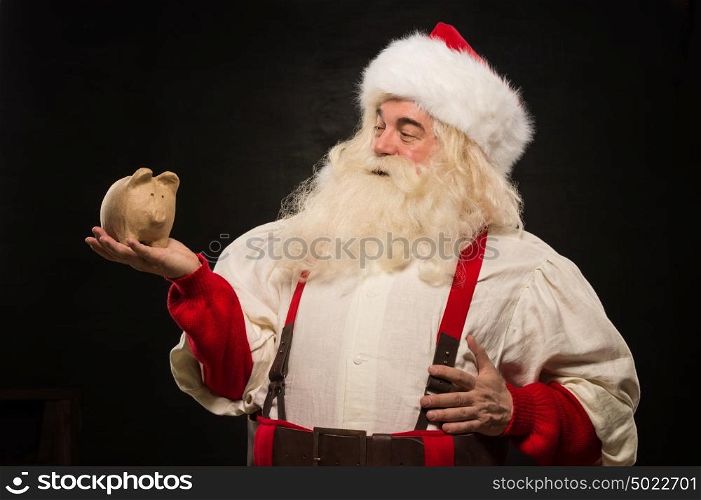 Santa Claus holding piggy bank moneybox. Christmas budget, banking and credits