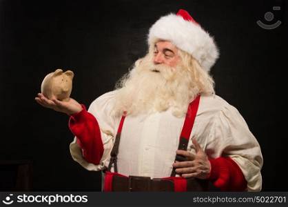 Santa Claus holding piggy bank moneybox. Christmas budget, banking and credits