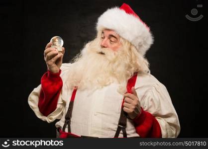 Santa Claus holding snow globe against dark background