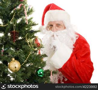 Santa Claus is very quiet as he leaves gifts on Christmas morning. Isolated on white.