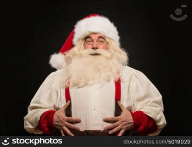 Santa Claus laughing loudly and holding his belly against dark background
