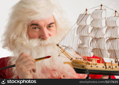 Santa Claus making toys. Painting and coloring wooden ship