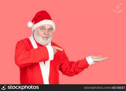 Santa Claus pointing something with his finger isolated on a red background
