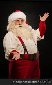 Santa Claus portrait expressing gesturing and presenting something against dark background