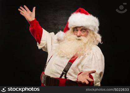 Santa Claus portrait expressing gesturing and presenting something against dark background