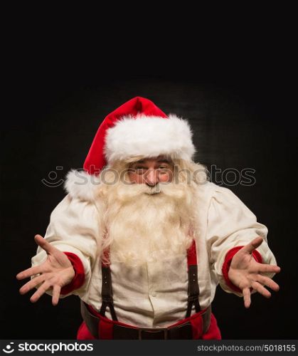 Santa Claus portrait expressing gesturing and presenting something against dark background. Lots of copyspace