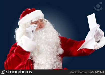 santa claus reading a letter. Santa Claus holding and reading a letter to him