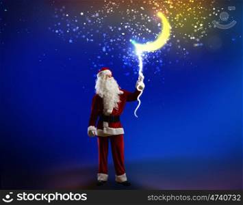 Santa Claus. Santa Claus holding moon in night sky on rope