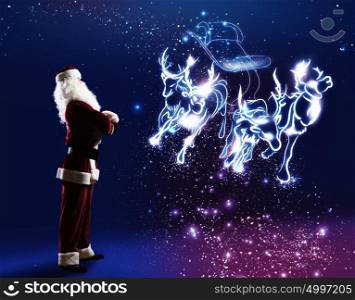 Santa Claus. Santa claus looking at magic image of sledge with deer