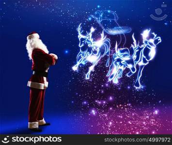 Santa Claus. Santa claus looking at magic image of sledge with deer