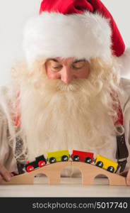 Santa Claus sitting and playing with railway toy at home
