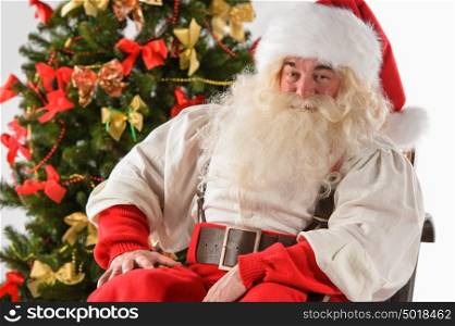 Santa Claus sitting in rocking chair near Christmas Tree at home