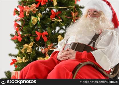 Santa Claus sitting in rocking chair near Christmas Tree at home and sleeping