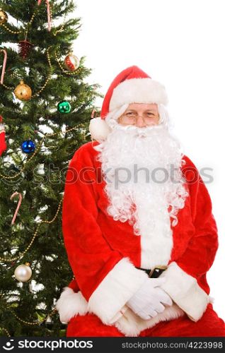 Santa Claus sitting under the Christmas tree. Isolated on white.