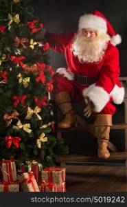 Santa Claus standing near Christmas tree in dark room