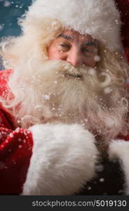 Santa Claus standing outdoors at snowfall at north pole with hands folded