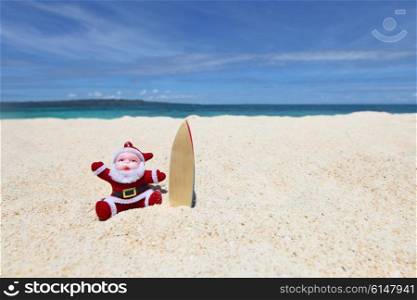 Santa Claus surfer on sand at tropical ocean beach, Christmas and New Year winter vacation concept