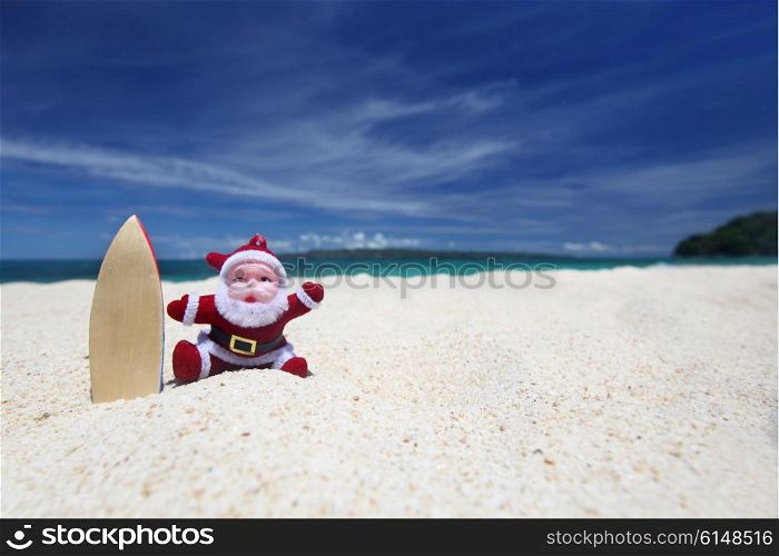Santa Claus surfer on sand at tropical ocean beach, Christmas and New Year winter vacation concept