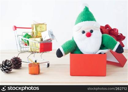 Santa Claus toy in red gift box with shopping cart with full of gift boxes, Merry Christmas