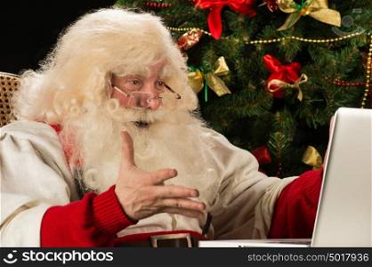 Santa Claus using laptop at home against Christmas Tree and is really impressed