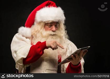 Santa Claus using tablet computer to surf internet and communicate in social media with children
